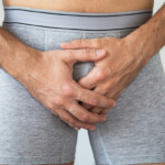 Beschneidung Symbolbild: Bildausschnitt eines männlichen Genitalbereichs in Unterhose, bei dem die Hände vor das Geschlechtsteil gelegt sind. Englisch: Circumcision Symbolic image: detail of a male genital area in underpants, with the hands placed in front of the genitals.