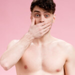 Angstspiele: Ein Mann mit freiem Oberkörper hält sich vor Entsetzen die Hand vor den Mund. Englisch: Fear play: A man with his upper body exposed covers his mouth in horror.