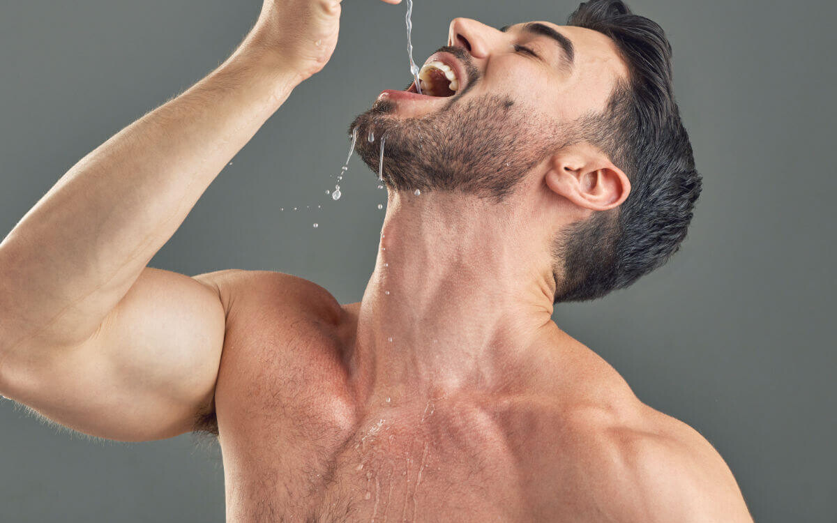 Gagging Symbolic image: A man with a bare upper body allows water to drip deep into his throat.