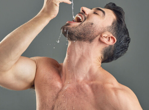 Gagging Symbolic image: A man with a bare upper body allows water to drip deep into his throat.