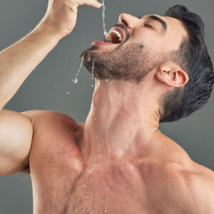 Gagging Symbolbild: Ein Mann mit nacktem Oberkörper lässt sich Wasser tief in den Hals tropfen.