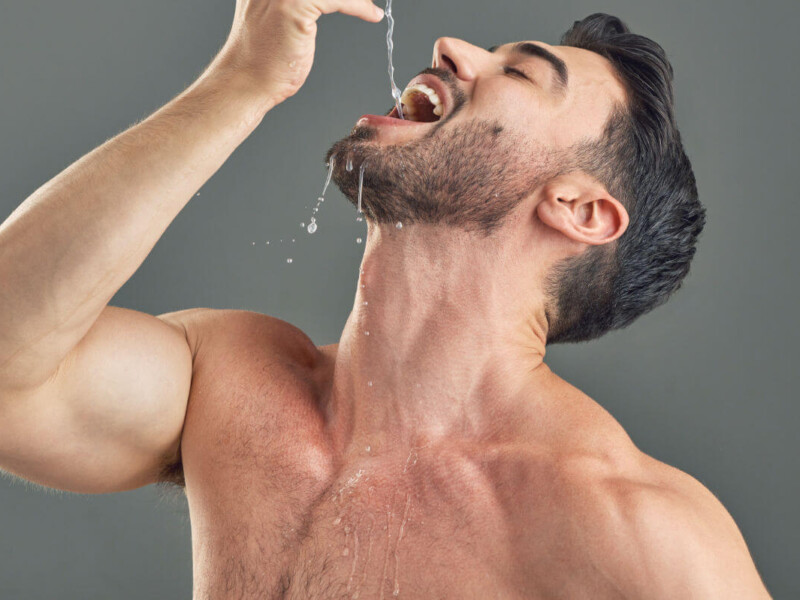 Gagging Symbolbild: Ein Mann mit nacktem Oberkörper lässt sich Wasser tief in den Hals tropfen.