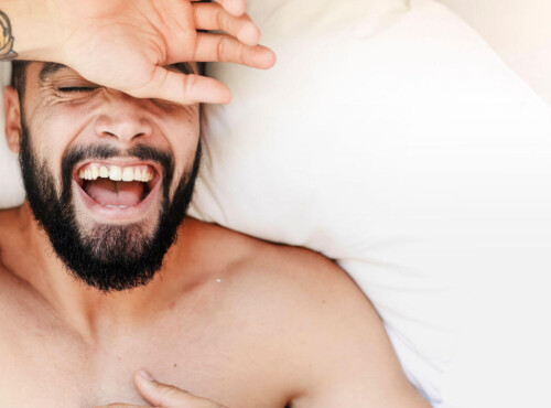 Ist Masturbieren gesund? Symbolbild: Gesicht eines Mannes, der sehr glücklich im Bett liegt. Is masturbation healthy? Symbolic image: Face of a man lying very happily in bed.