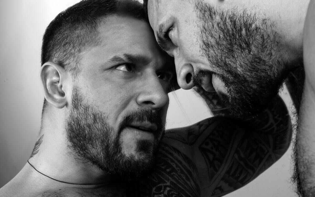 BDSM-Prinzipien Symbolbild: Schwarz-Weiß-Bild. Zwei Männer halten die Köpfe zusammen und sehen sich intensiv in die Augen. BDSM principles Symbolic image: Black and white image. Two men hold their heads together and look intensely into each other's eyes.