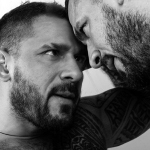 BDSM-Prinzipien Symbolbild: Schwarz-Weiß-Bild. Zwei Männer halten die Köpfe zusammen und sehen sich intensiv in die Augen. BDSM principles Symbolic image: Black and white image. Two men hold their heads together and look intensely into each other's eyes.