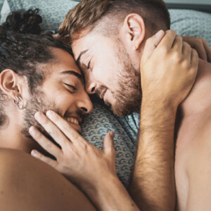 Frotting vs. Dry Humping Symbolbild: Zwei Männer liegen nackt im Bett und kuscheln. Frotting vs. Dry Humping Symbolic image: Two men lying naked in bed and cuddling.