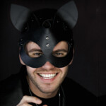 Kittenplay Symbolbild: Mann mit schwarzer Katzenmaske lächelt in die Kamera. . Kitten play Symbolic image: Man wearing a black cat mask smiles at the camera.