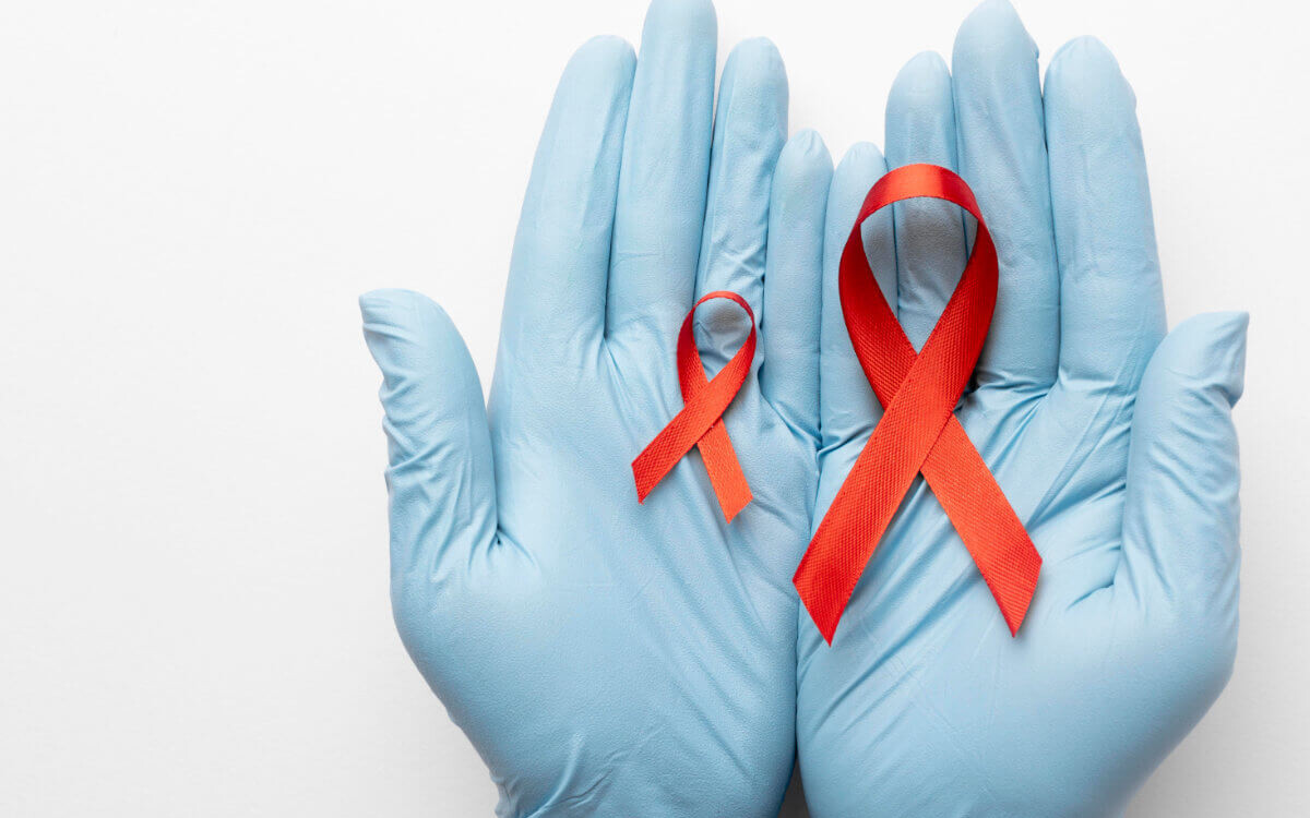 TasP Symbolbild: Zwei Hände mit medizinischen Handschuhen halten eine große und eine kleine Aids-Schleife. TasP Symbolic image: Two hands wearing medical gloves hold a large and a small AIDS ribbon.