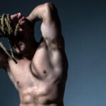 Shibari vs. Kinbaku Symbolbild: Nackter männlicher Oberkörper, das Gesicht wird von einem dicken Seil verdeckt. Englisch: Shibari vs. Kinbaku Symbolic image: Naked male torso, face covered by a thick rope.
