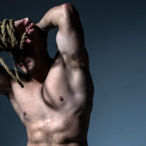 Shibari vs. Kinbaku Symbolbild: Nackter männlicher Oberkörper, das Gesicht wird von einem dicken Seil verdeckt. Englisch: Shibari vs. Kinbaku Symbolic image: Naked male torso, face covered by a thick rope.