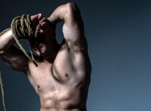 Shibari vs. Kinbaku Symbolbild: Nackter männlicher Oberkörper, das Gesicht wird von einem dicken Seil verdeckt. Englisch: Shibari vs. Kinbaku Symbolic image: Naked male torso, face covered by a thick rope.