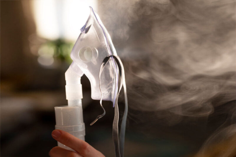 Poppers Alternativen: Inhalationsmaske mit sichtbarem Dampf in der Hand Englisch: Poppers Alternatives: inhalation mask with visible vapor held in hand