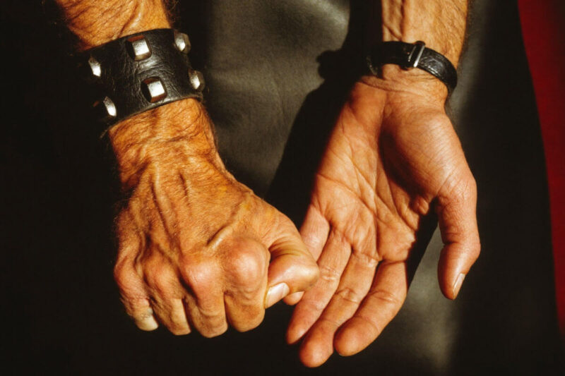 Nahaufnahme von zwei Händen mit Lederarmbändern: Eine Hand formt eine geschlossene Faust, die andere ist geöffnet. Das Bild veranschaulicht eine Handposition im Kontext von Fisting Grifftechniken und legt den Fokus auf Präzision, Kontrolle und Vorbereitung. EN: Close-up of two hands wearing leather wristbands: one hand is clenched into a fist while the other is open. The image illustrates a hand position in the context of Fisting grip techniques, emphasizing precision, control, and preparation.
